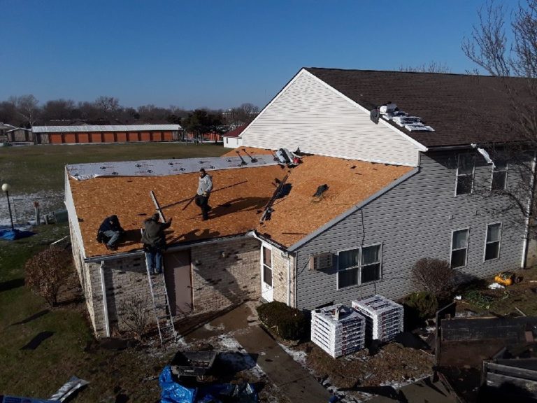 Crew installing a new shingle roof on a multi-unit residential building