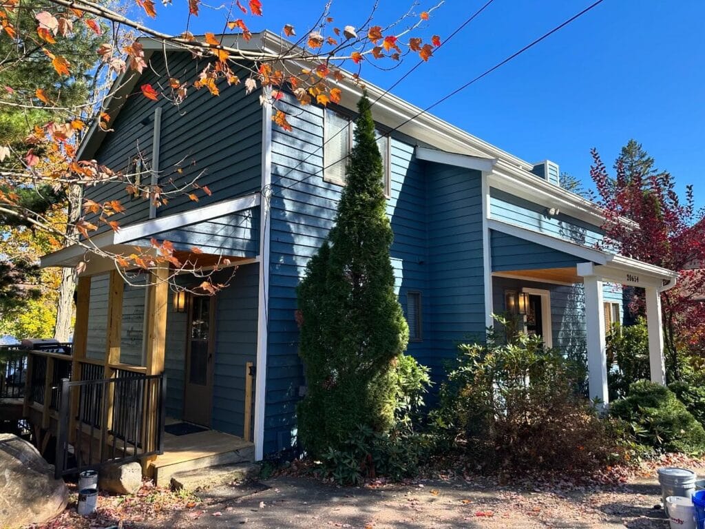 Two-story blue home with a side deck and new roof