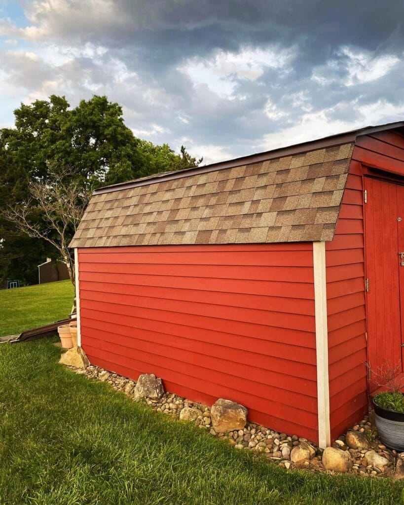 Red outbuilding with a new shingle roof