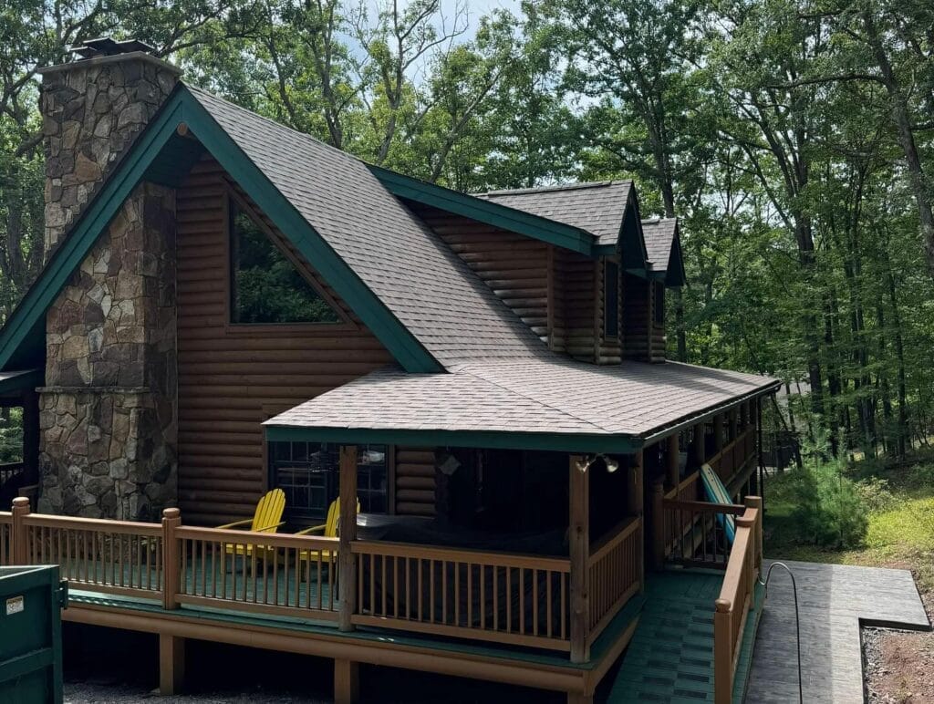 Log home with a covered porch, deck railings and a new shingle roof