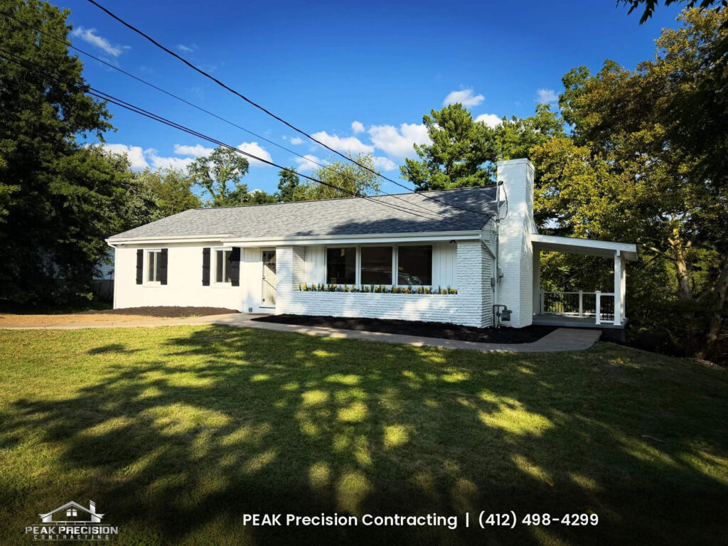 exterior-home-renovation-bethel-park-pa_exterior Renovated ranch home with painted white brick, board-and-batten siding accents, black shutters, a new shingle roof and a covered side porch, by Peak Precision Contracting