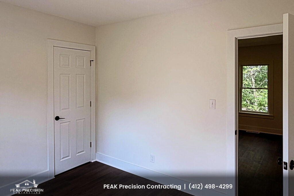 home-renovation-general-contractor-peters-township-pa_bedroom Renovated bedroom with new six-panel white doors, white trim, fresh paint and dark wood-look flooring, completed by Peak Precision Contracting
