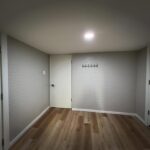 Finished lower-level room with painted brick wall and vinyl plank flooring by Peak Precision Contracting in Peters Township, PA
