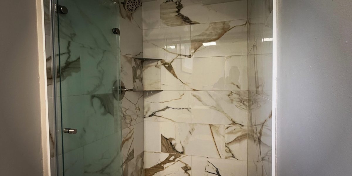 Walk-in shower with glass door and marble-look tile, remodeled by Peak Precision Contracting in Peters Township, PA