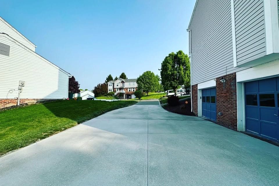 New concrete driveway beside a home with blue garage doors, poured by Peak Precision Contracting