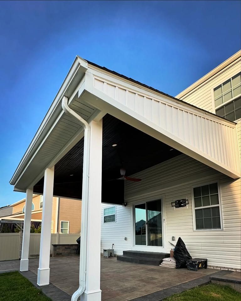 Covered back porch with white columns and a gable roof over a patio, built by Peak Precision Contracting