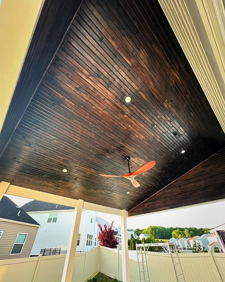 Stained wood porch ceiling with recessed lights and a ceiling fan on a covered porch by Peak Precision Contracting