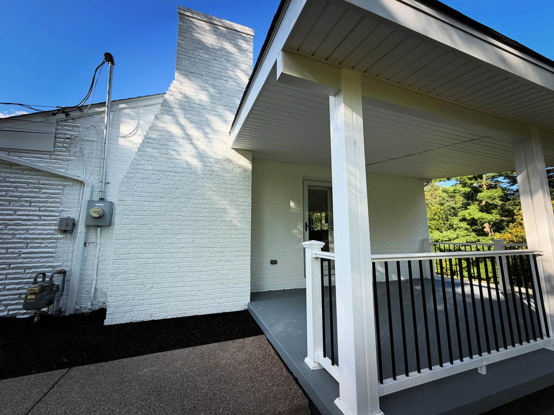Covered porch with white columns and black railings at a home renovated by Peak Precision Contracting in Peters Township, PA