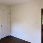 Freshly painted bedroom with new interior doors and vinyl plank flooring in a home renovated by Peak Precision Contracting