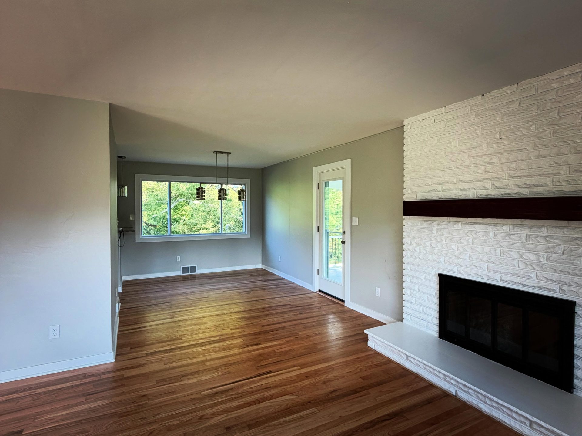 peak-precision-home-renovation-living-room-peters-township-pa-1 Renovated living and dining area with refinished hardwood floors and a painted brick fireplace, by Peak Precision Contracting in Peters Township, PA