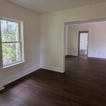 Freshly painted living area with two windows, white trim and dark plank flooring by Peak Precision Contracting