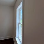 Freshly painted bedroom corner with a window and white trim by Peak Precision Contracting