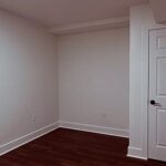 Freshly painted room with a white six-panel door and dark plank flooring by Peak Precision Contracting