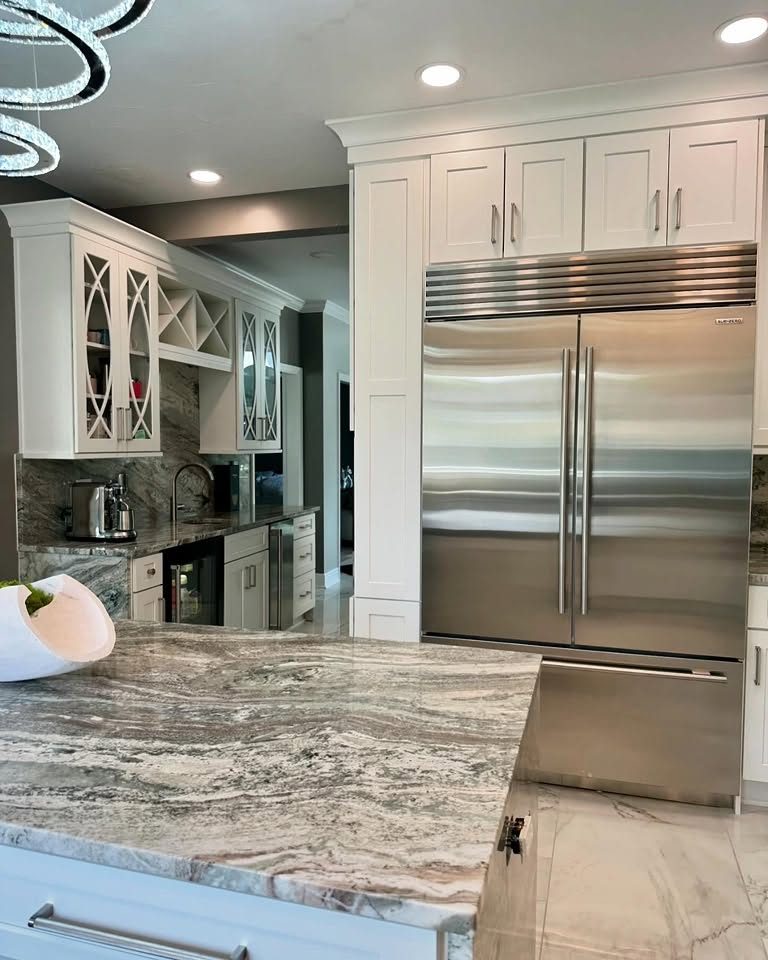 Kitchen remodel with white shaker cabinets, stainless refrigerator and stone island by Peak Precision Contracting