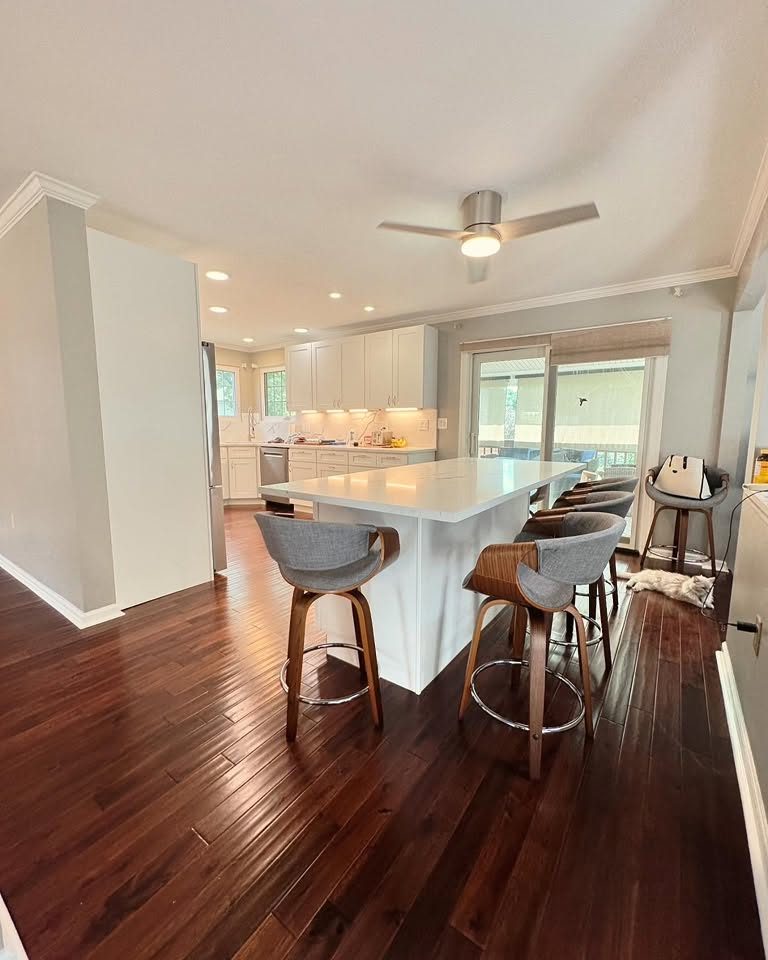 Kitchen remodel with a white island, counter stools and hardwood floors by Peak Precision Contracting