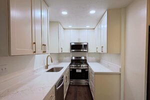 Galley kitchen with white cabinets, quartz countertops and brass faucet, remodeled by Peak Precision Contracting