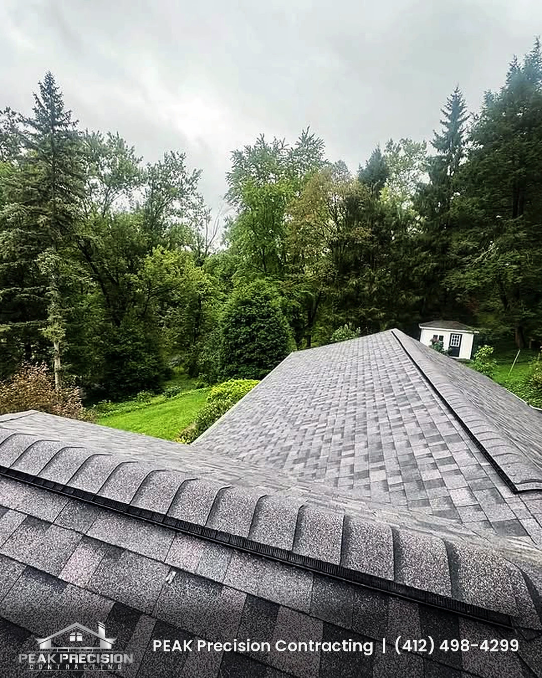 Ridge vent running along the peak of a new gray architectural shingle roof with a wooded backdrop, installed by Peak Precision Contracting