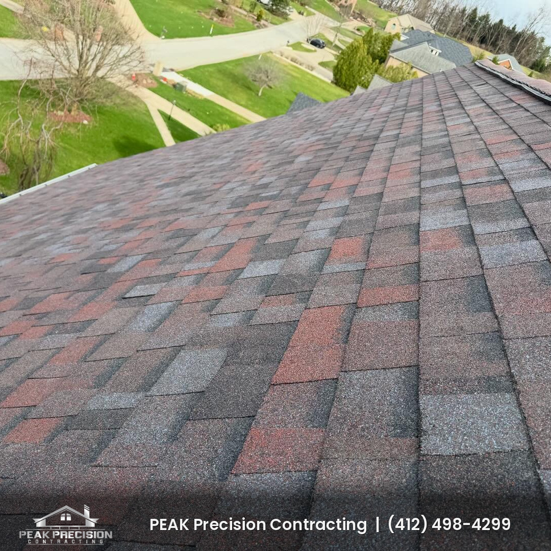 Close-up of a newly installed architectural shingle roof in a red and gray blend on a suburban home, installed by Peak Precision Contracting