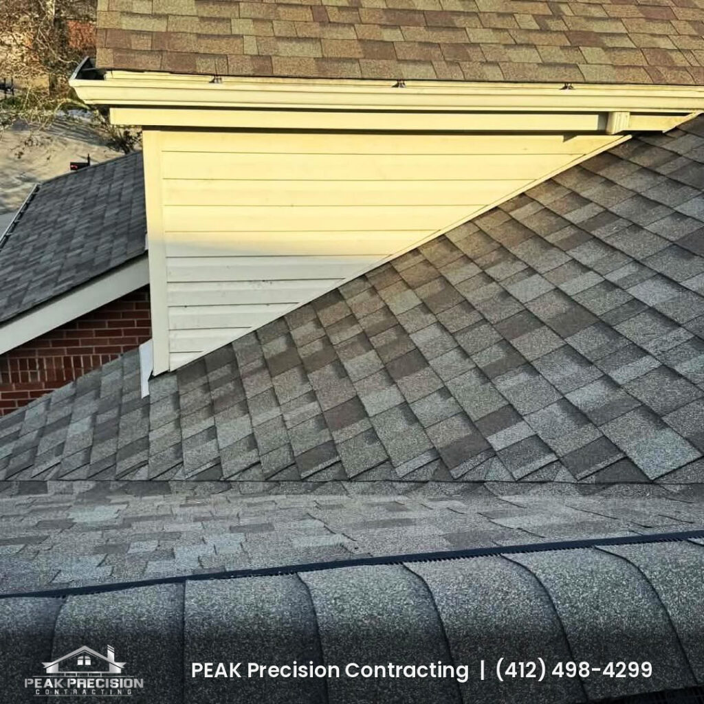 Roof-to-sidewall junction and ridge cap on a shingle roof completed by Peak Precision Contracting