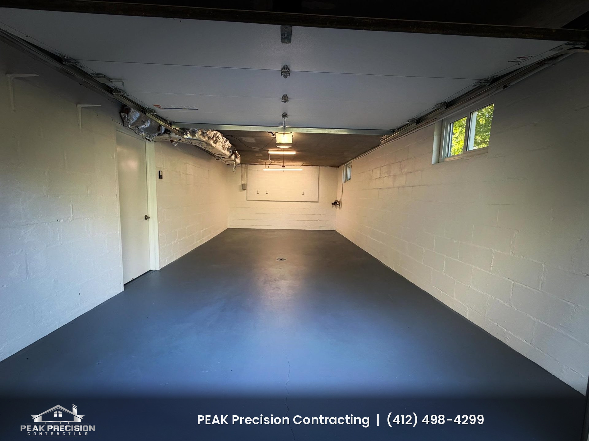 Garage interior with freshly painted white block walls and a gray painted concrete floor, finished by Peak Precision Contracting