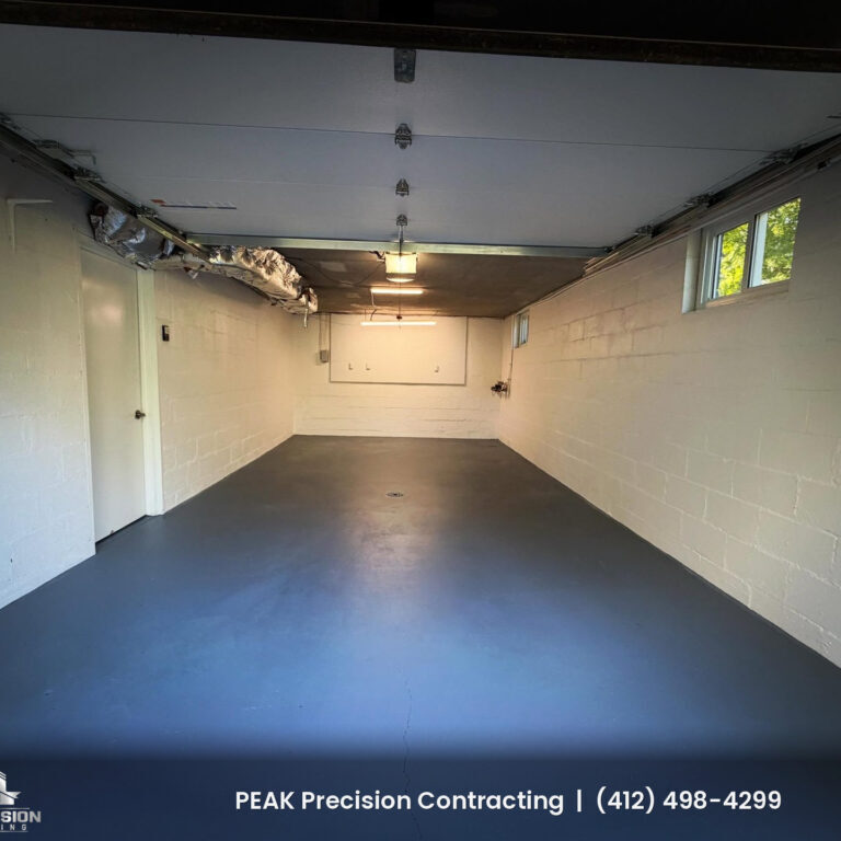 Garage interior with freshly painted white block walls and a gray painted concrete floor, finished by Peak Precision Contracting